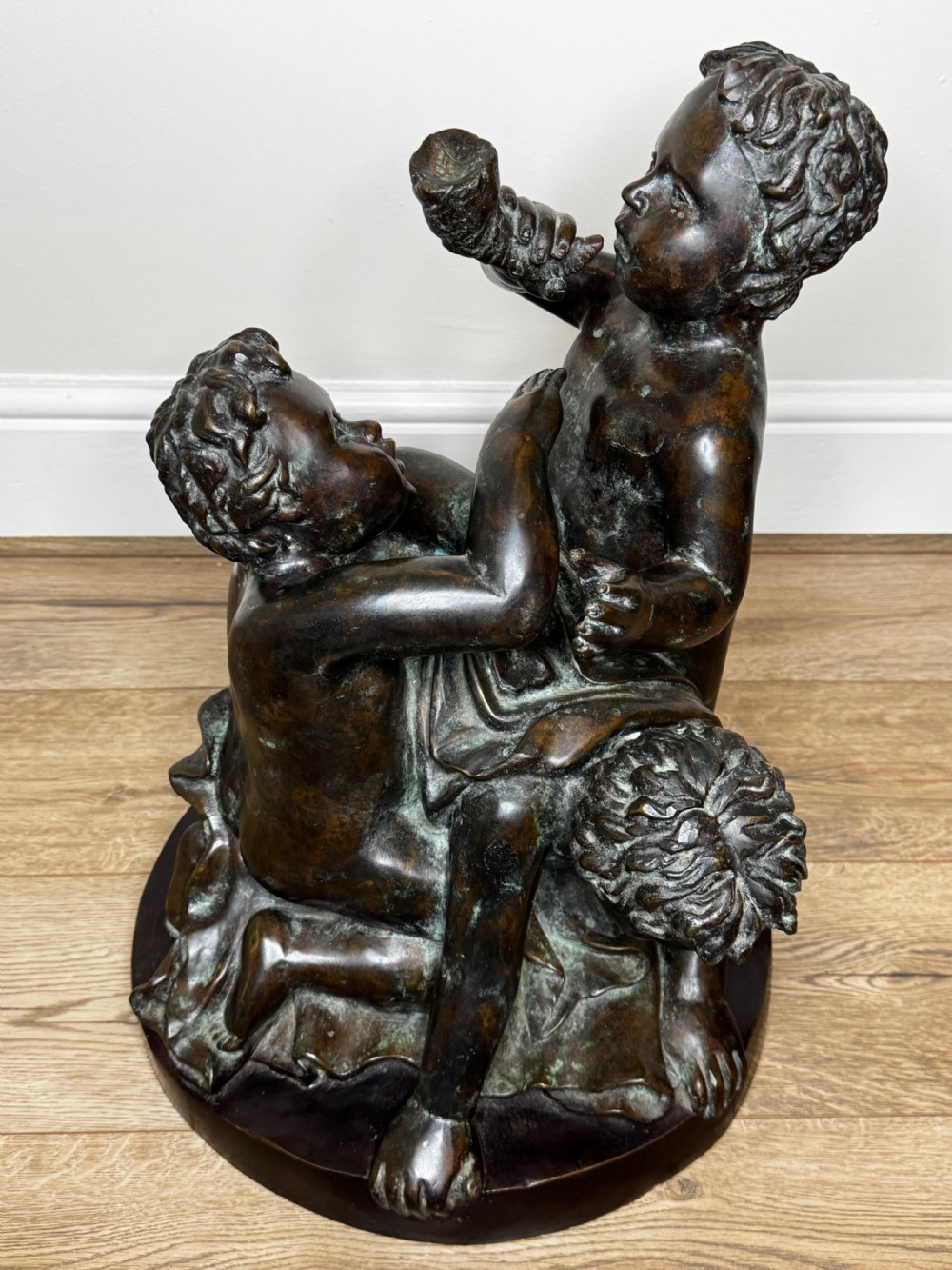 A dark patinated French bronze sculptural group depicting three putti playing, with one child blowing into a conch shell. View XX