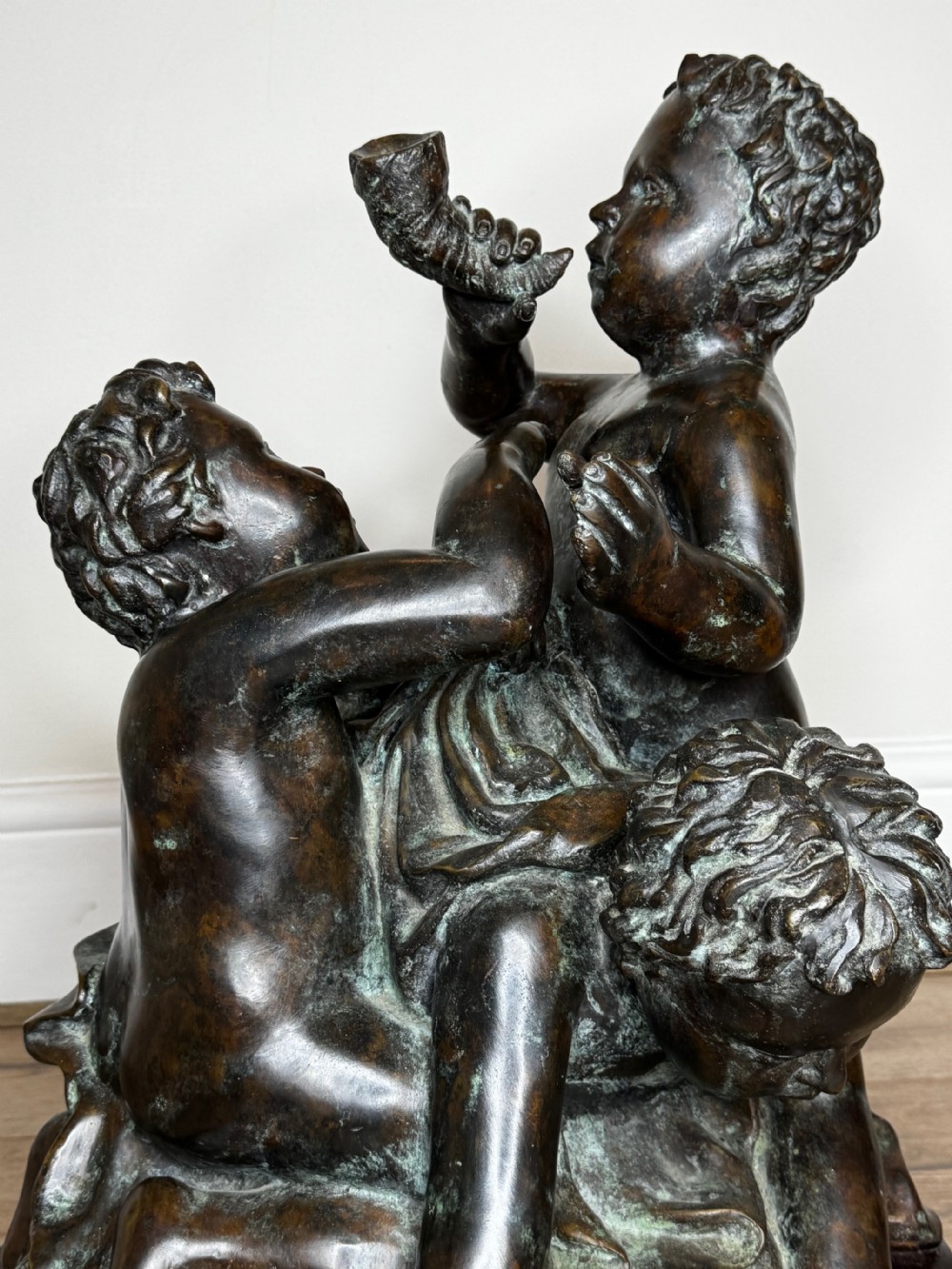 A dark patinated French bronze sculptural group depicting three putti playing, with one child blowing into a conch shell. View XXI