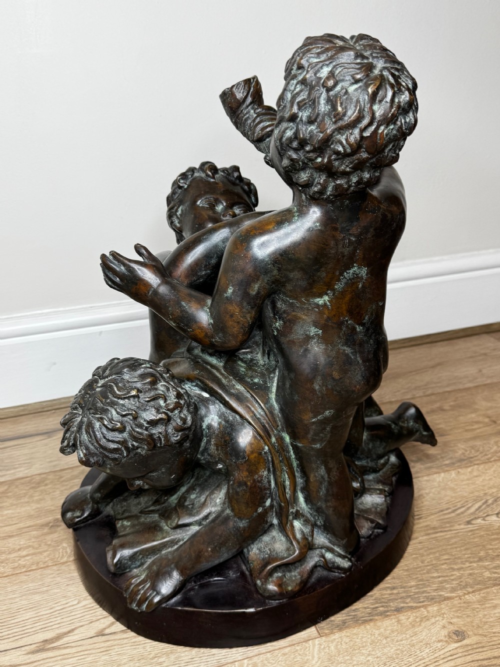 A dark patinated French bronze sculptural group depicting three putti playing, with one child blowing into a conch shell. View XXIX