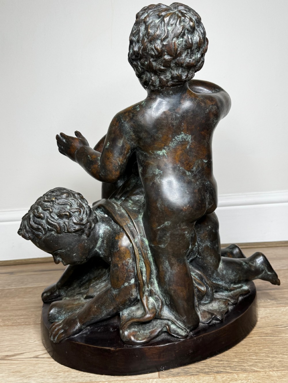 A dark patinated French bronze sculptural group depicting three putti playing, with one child blowing into a conch shell. View XXX