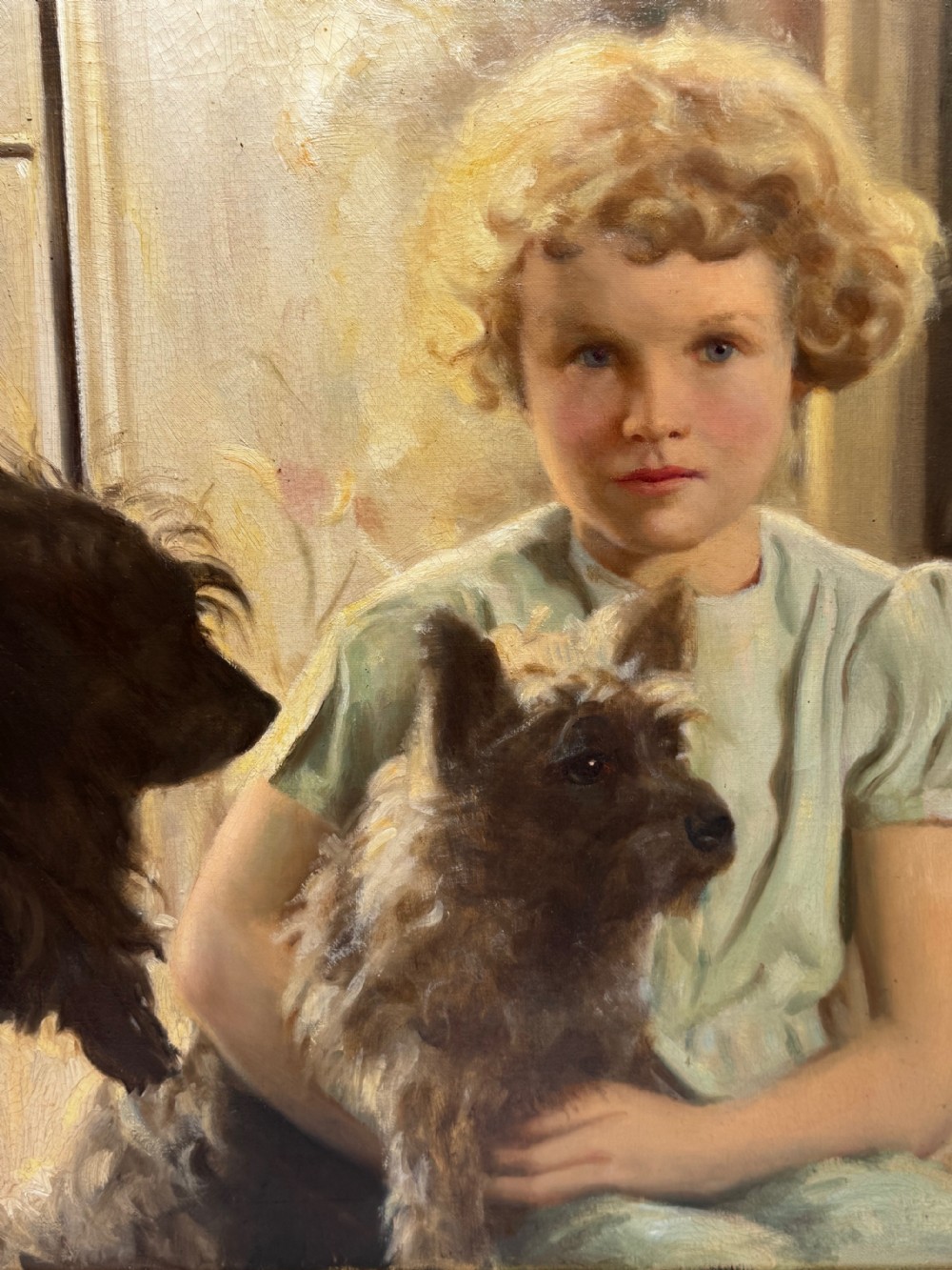 A mid-20th-century oil portrait depicting a young girl with blonde curly hair holding a Cairn Terrier. View V