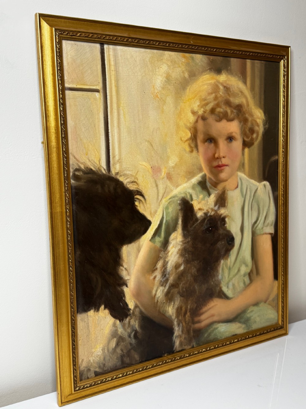 A mid-20th-century oil portrait depicting a young girl with blonde curly hair holding a Cairn Terrier. View VI