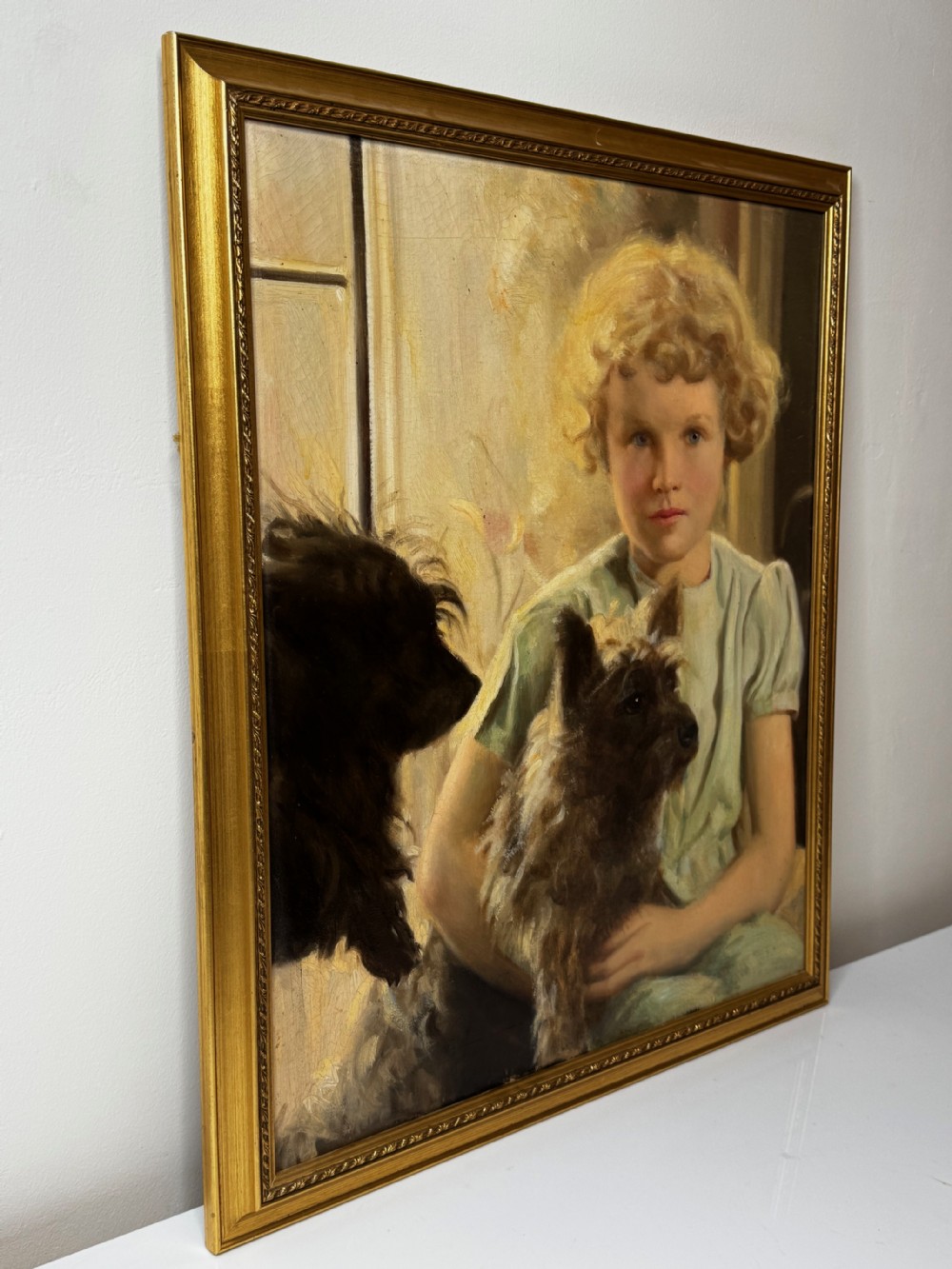 A mid-20th-century oil portrait depicting a young girl with blonde curly hair holding a Cairn Terrier. View VII