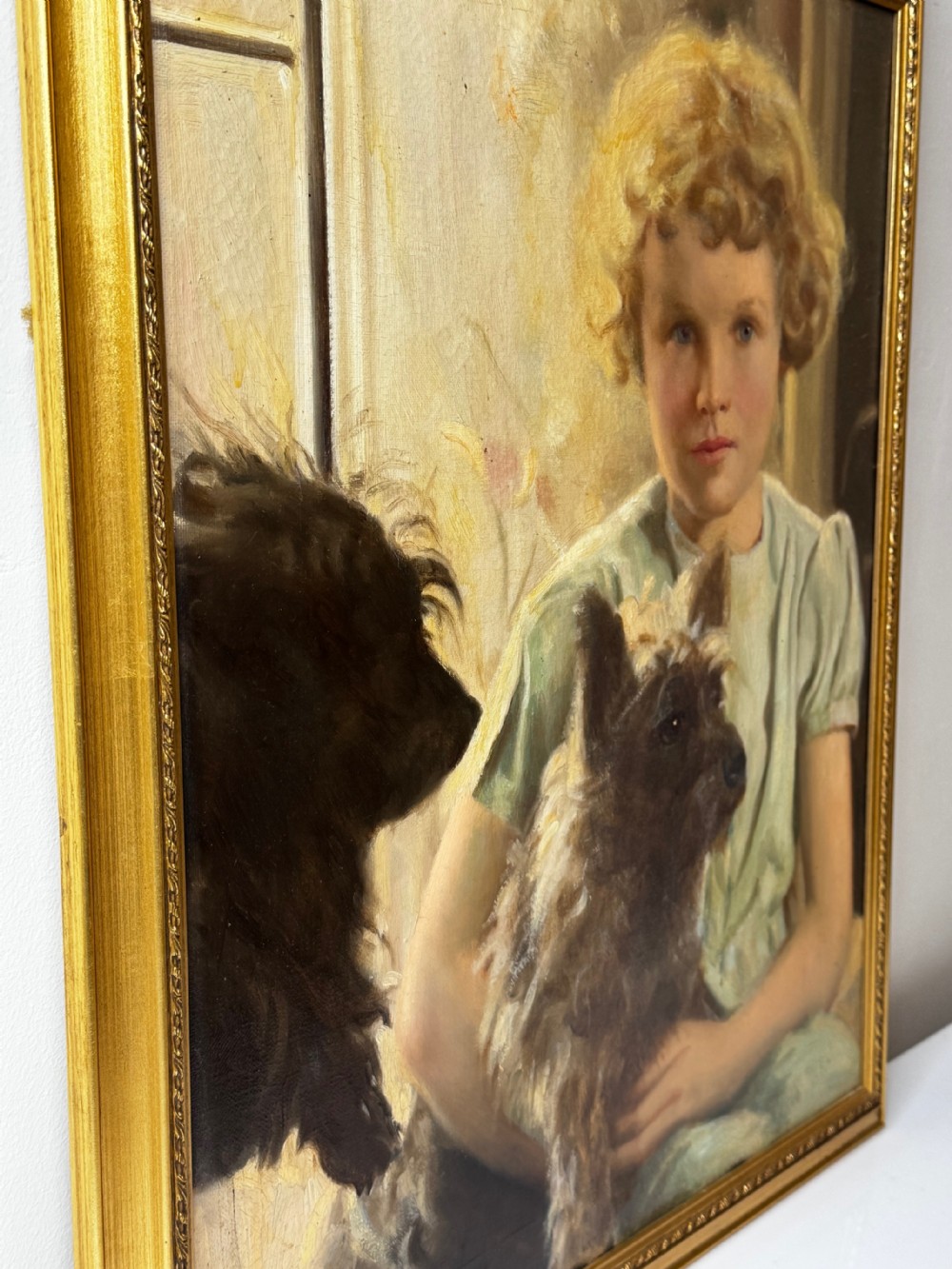 A mid-20th-century oil portrait depicting a young girl with blonde curly hair holding a Cairn Terrier. View VIII