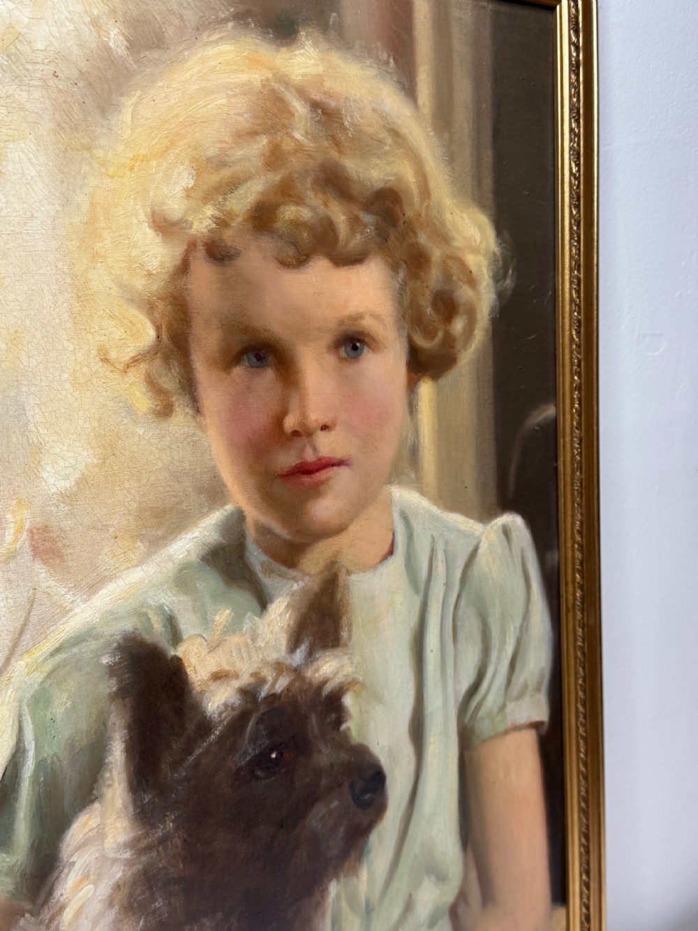 A mid-20th-century oil portrait depicting a young girl with blonde curly hair holding a Cairn Terrier. View XI