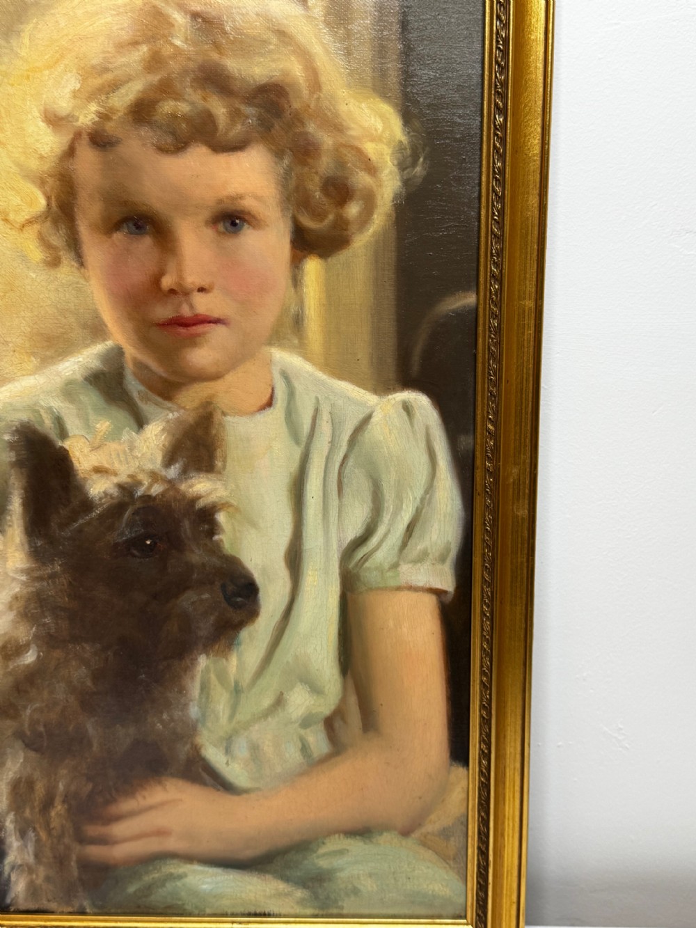 A mid-20th-century oil portrait depicting a young girl with blonde curly hair holding a Cairn Terrier. View XIV