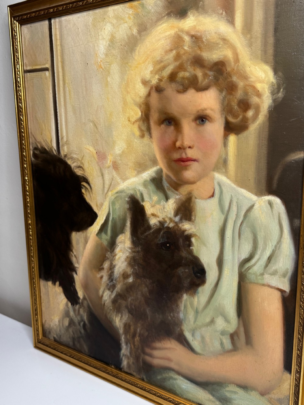 A mid-20th-century oil portrait depicting a young girl with blonde curly hair holding a Cairn Terrier. View XV