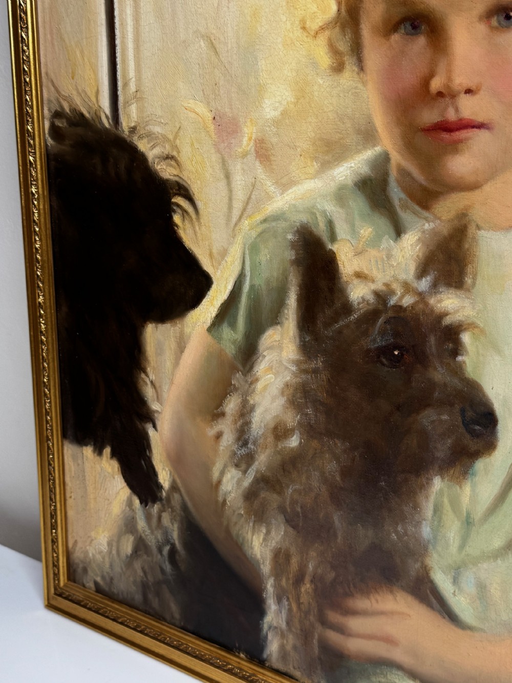A mid-20th-century oil portrait depicting a young girl with blonde curly hair holding a Cairn Terrier. View XVI