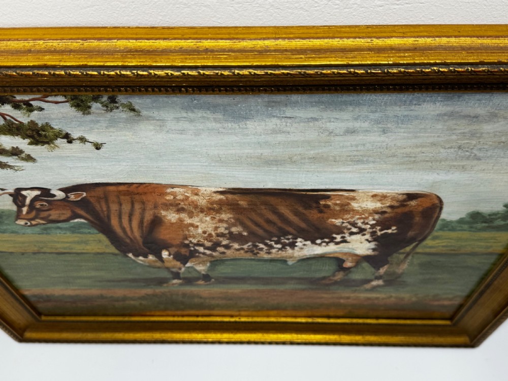 A 19th-century oil painting depicting a brown and white shorthorn bull standing in side profile in a green field, encased in a gilded frame. View V