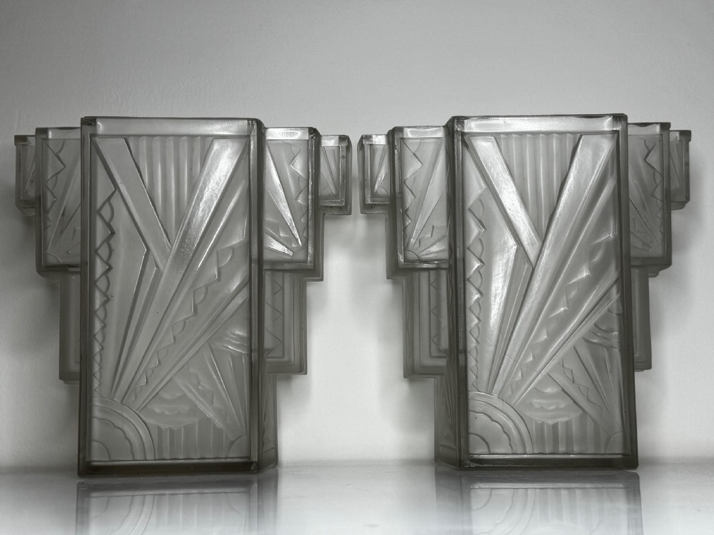 A pair of Art Deco frosted moulded glass wall lights featuring a stepped skyscraper silhouette with geometric sunburst and chevron carvings. View XIV