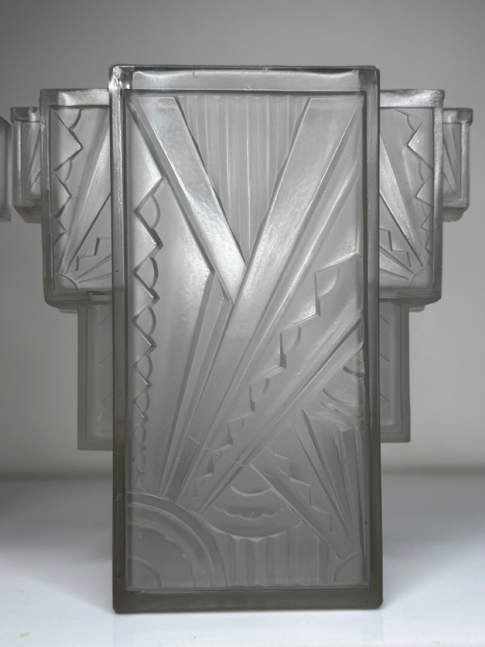 A pair of Art Deco frosted moulded glass wall lights featuring a stepped skyscraper silhouette with geometric sunburst and chevron carvings. View XXIII