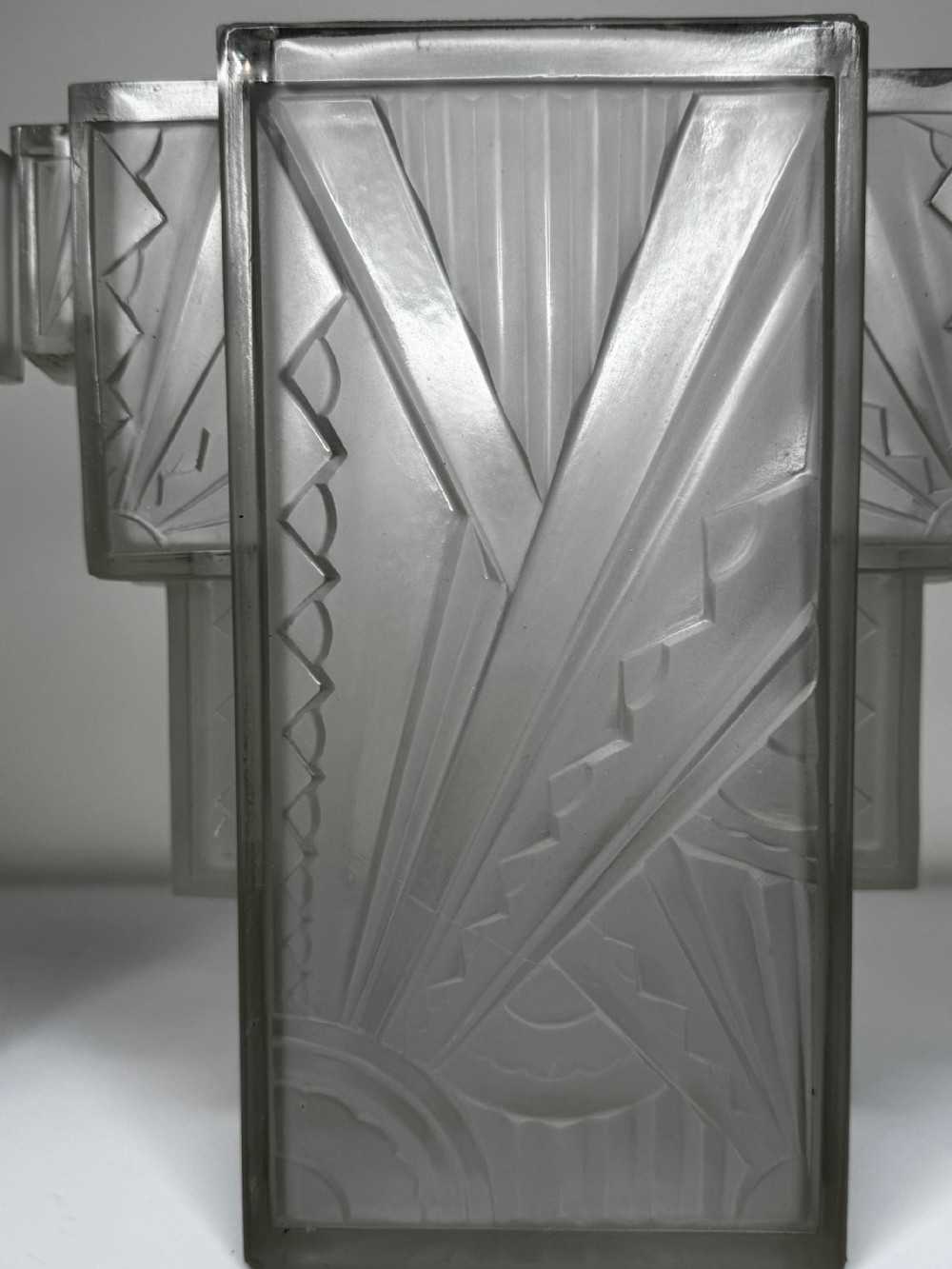 A pair of Art Deco frosted moulded glass wall lights featuring a stepped skyscraper silhouette with geometric sunburst and chevron carvings. View XXIV