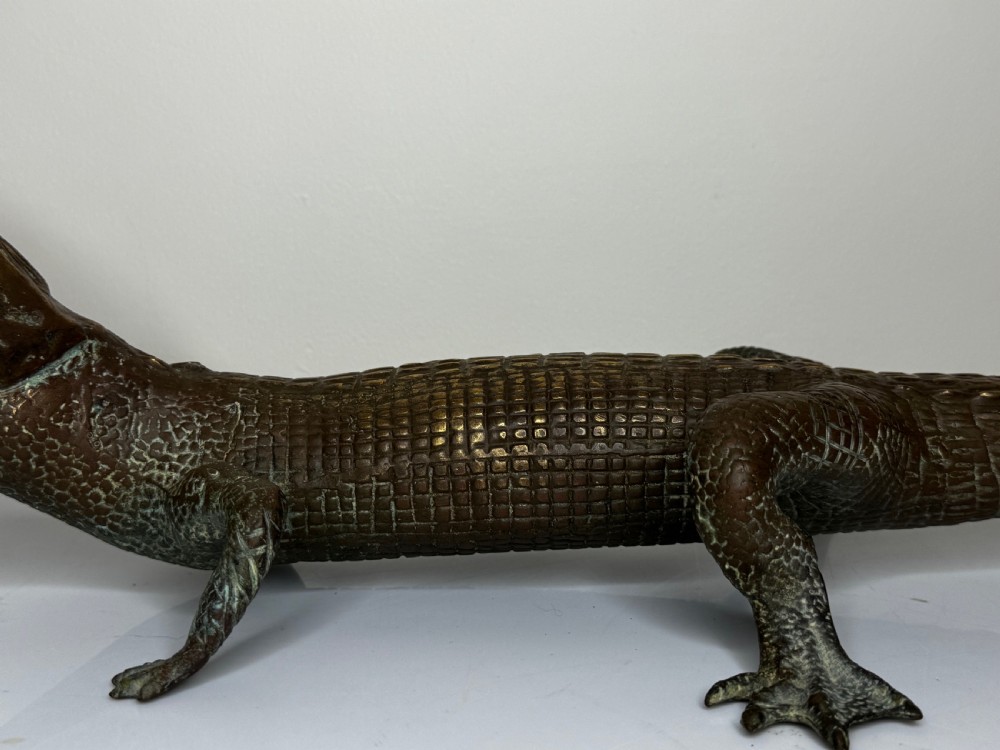 A dark bronze sculpture of a crocodile with an open mouth, detailed scales, and a curved tail designed as a water fountain spout. View XVII