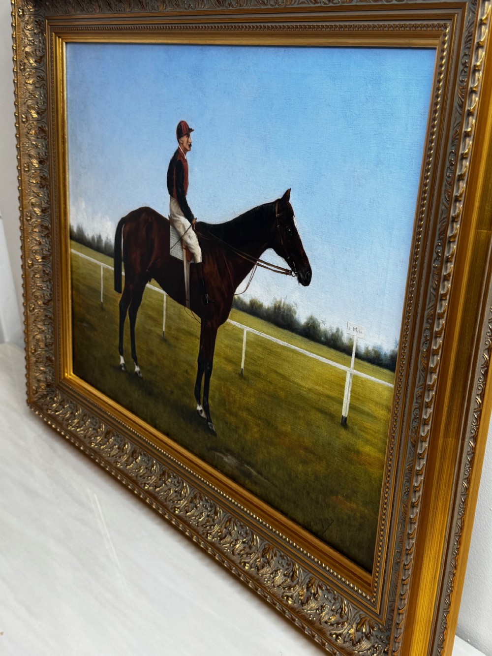 A framed Victorian oil painting depicting a bay racehorse and mounted jockey against a blue sky and green racecourse backdrop. View IX