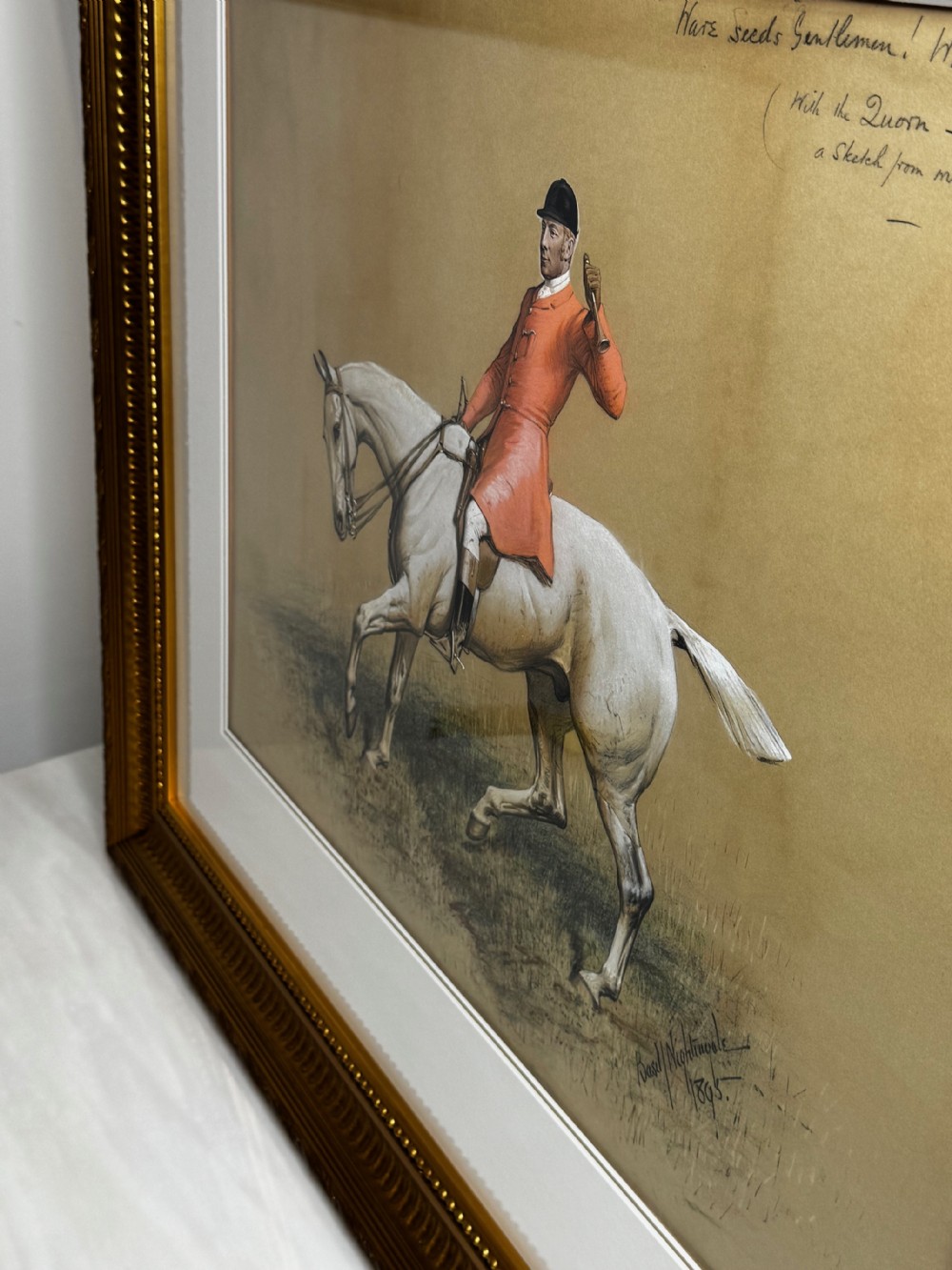 A framed Victorian equestrian painting depicting a huntsman in a red coat riding a grey horse, set within a gilt moulded frame. View X