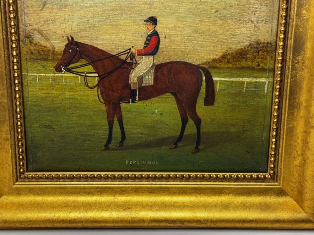 An oil painting depicting a brown thoroughbred racehorse with a jockey in red and blue silks, set within a wide gilded frame. View II