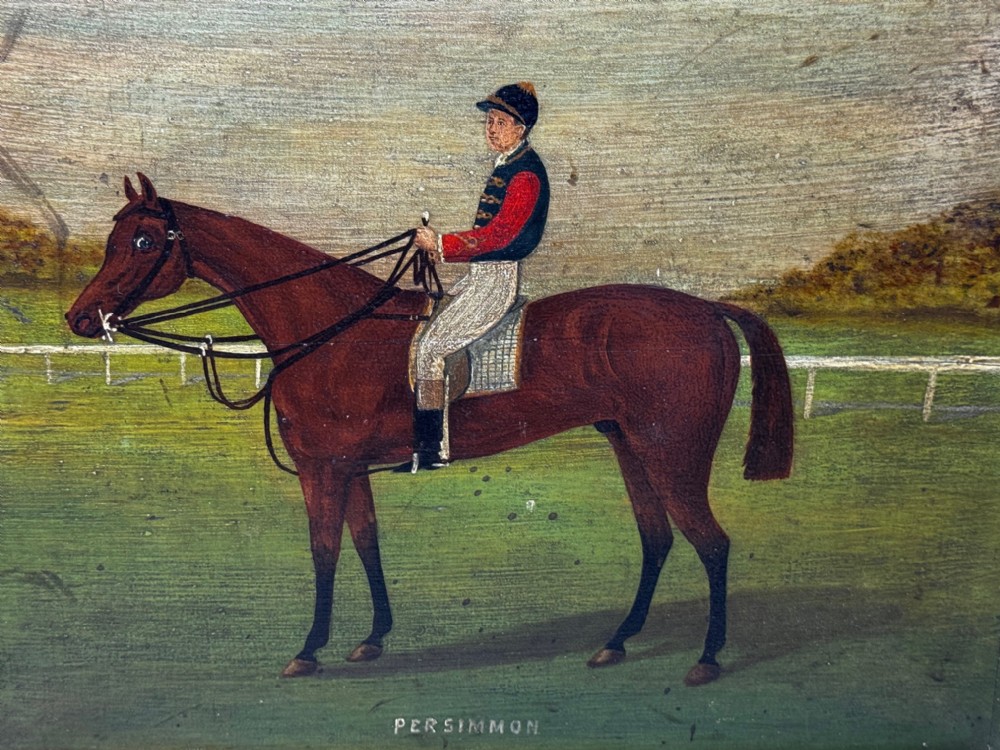 An oil painting depicting a brown thoroughbred racehorse with a jockey in red and blue silks, set within a wide gilded frame. View V