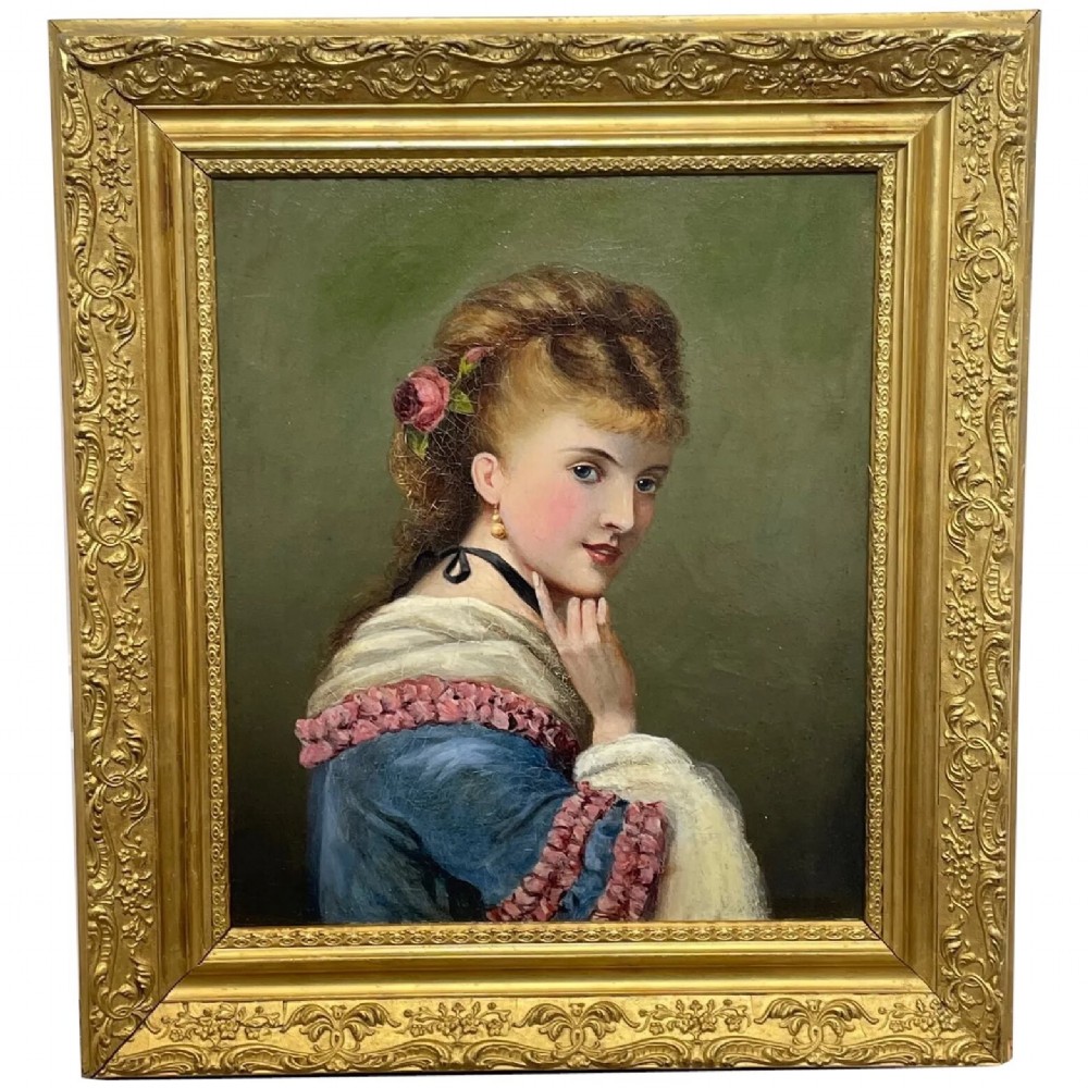 A Victorian oil portrait depicting a young woman with a flower in her hair wearing a blue dress, set within an ornate gilt frame.