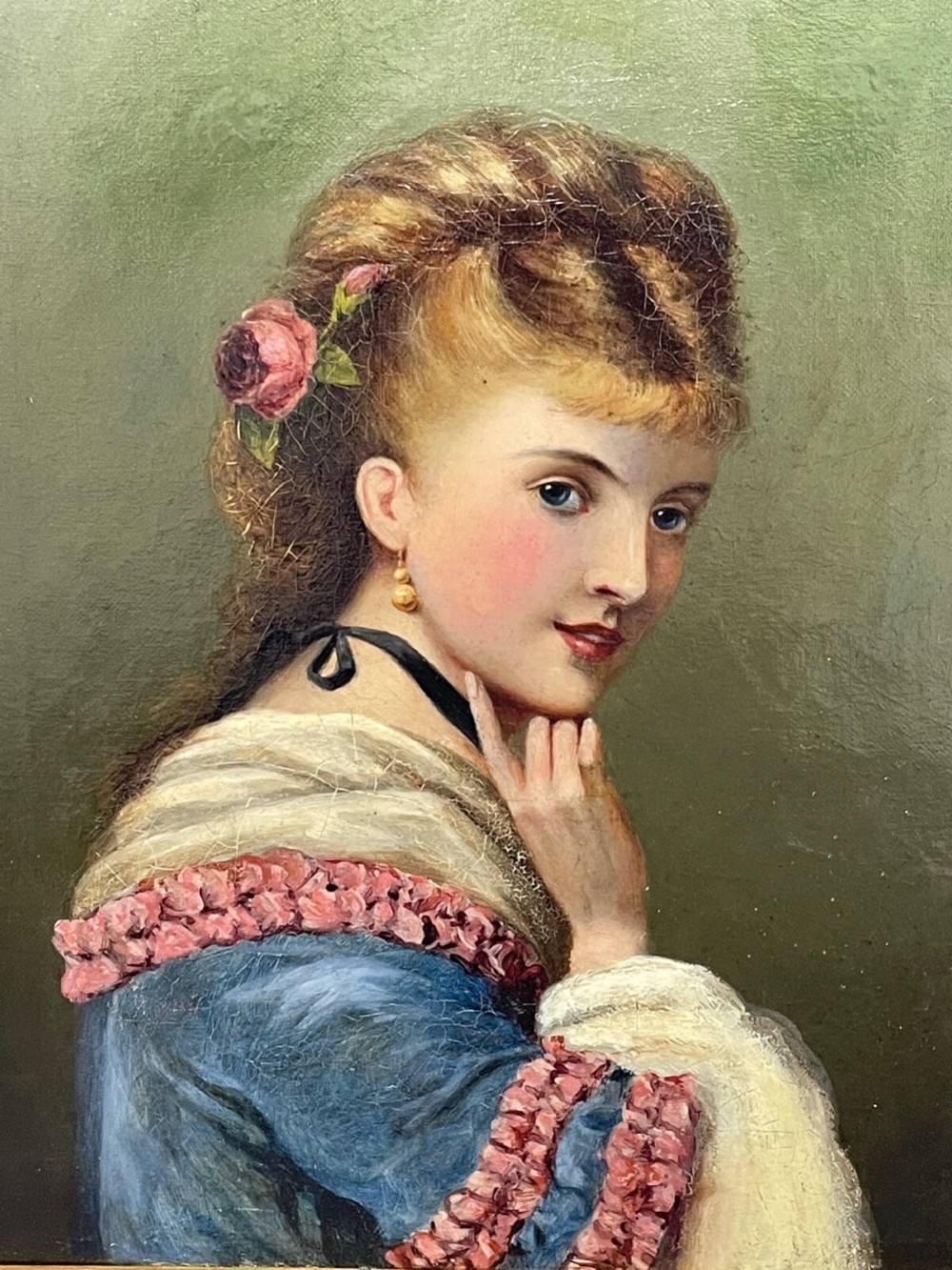 A Victorian oil portrait depicting a young woman with a flower in her hair wearing a blue dress, set within an ornate gilt frame. View III