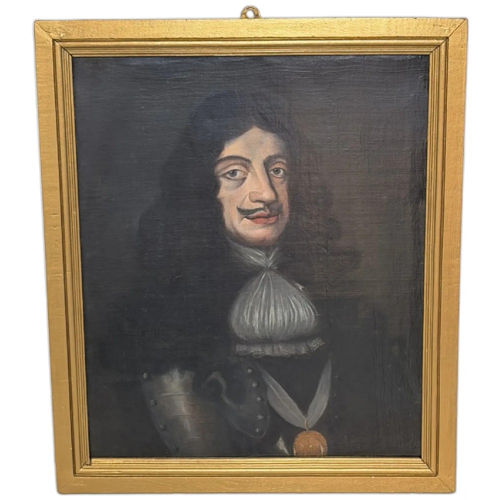 A 19th-century framed oil portrait depicting King Charles II wearing armour, a white lace cravat, and the Order of the Garter medallion against a dark background.