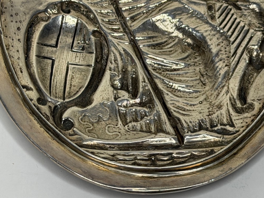 An oval George III sterling silver plaque featuring an embossed relief of Britannia holding a spear beside a shield and harp with embossed text reading London Assurance. View IX
