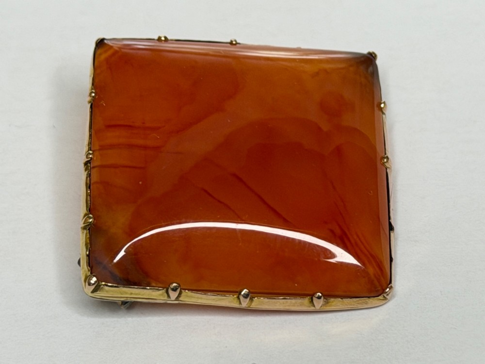 A square-cut translucent warm orange carnelian agate gemstone held in a 9ct gold frame with claw settings. View II