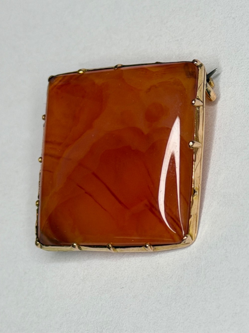 A square-cut translucent warm orange carnelian agate gemstone held in a 9ct gold frame with claw settings. View III