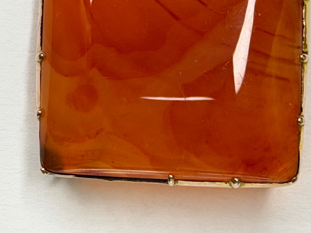 A square-cut translucent warm orange carnelian agate gemstone held in a 9ct gold frame with claw settings. View V