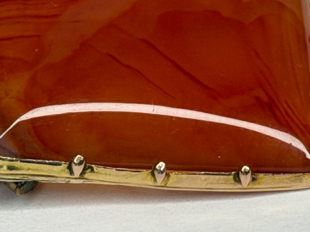 A square-cut translucent warm orange carnelian agate gemstone held in a 9ct gold frame with claw settings. View VI