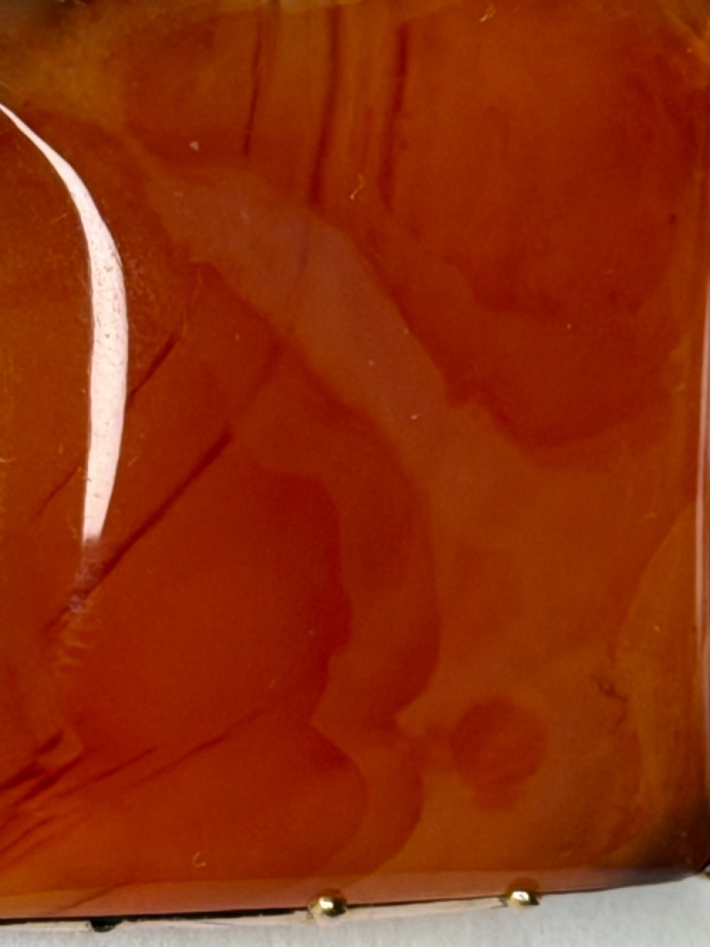 A square-cut translucent warm orange carnelian agate gemstone held in a 9ct gold frame with claw settings. View VII
