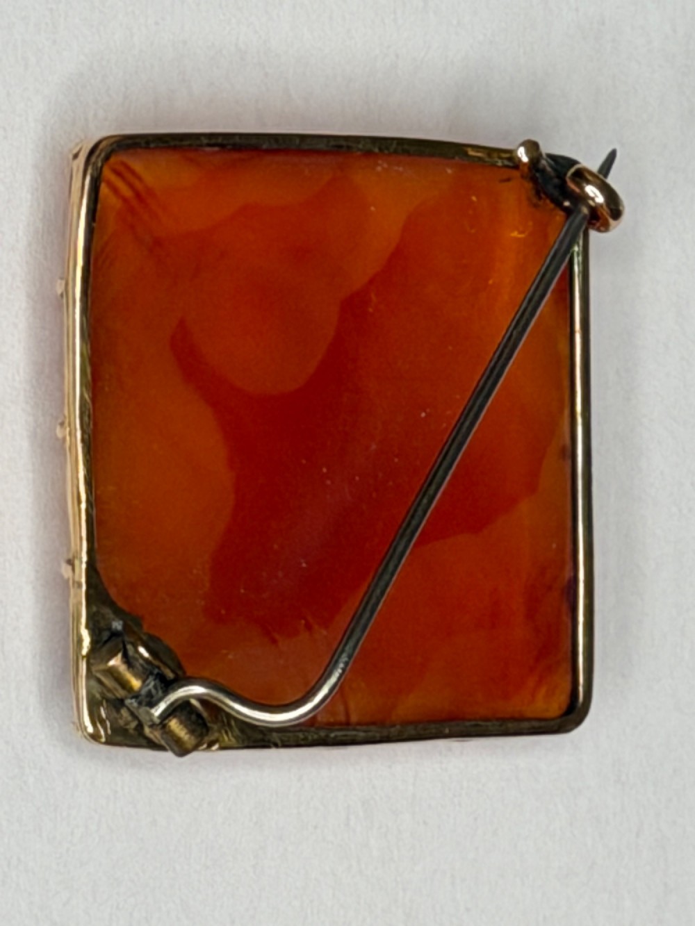 A square-cut translucent warm orange carnelian agate gemstone held in a 9ct gold frame with claw settings. View IX
