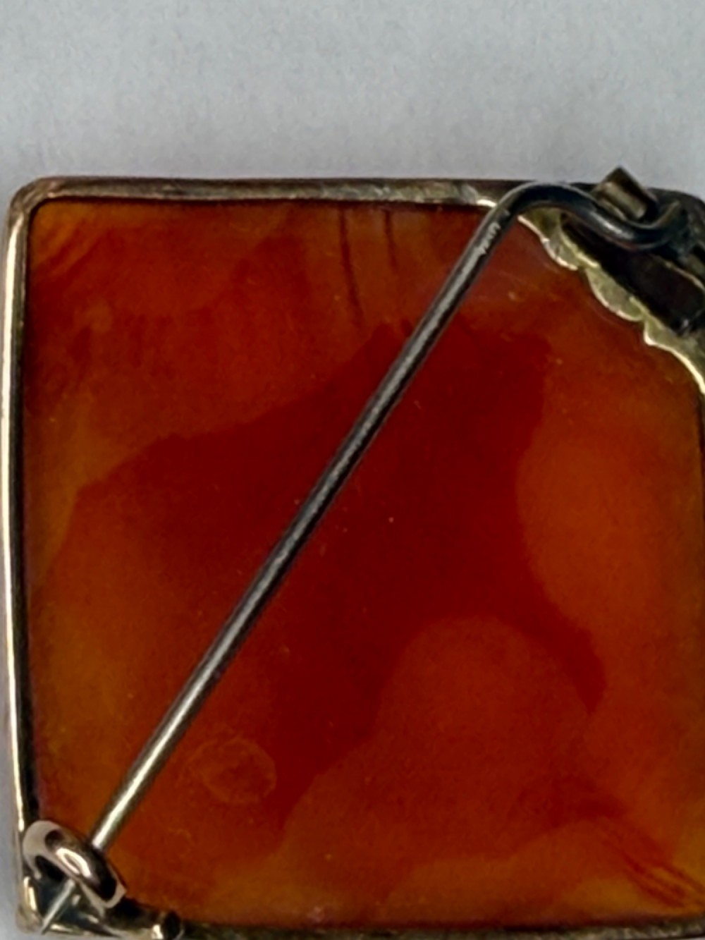 A square-cut translucent warm orange carnelian agate gemstone held in a 9ct gold frame with claw settings. View X
