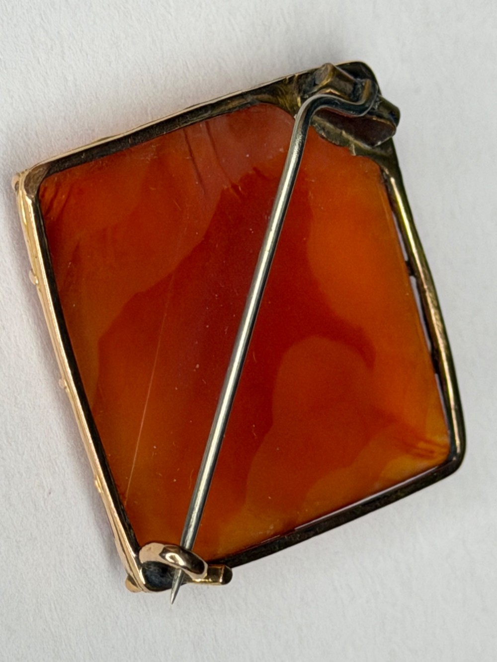 A square-cut translucent warm orange carnelian agate gemstone held in a 9ct gold frame with claw settings. View XI