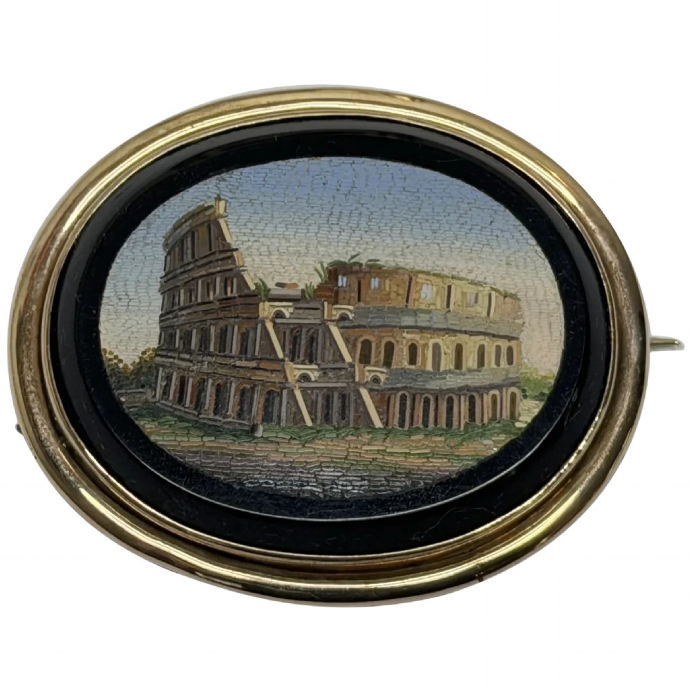 An oval nineteenth-century micromosaic brooch set in a yellow gold bezel depicting the Roman Colosseum against a light blue sky within a black surround.