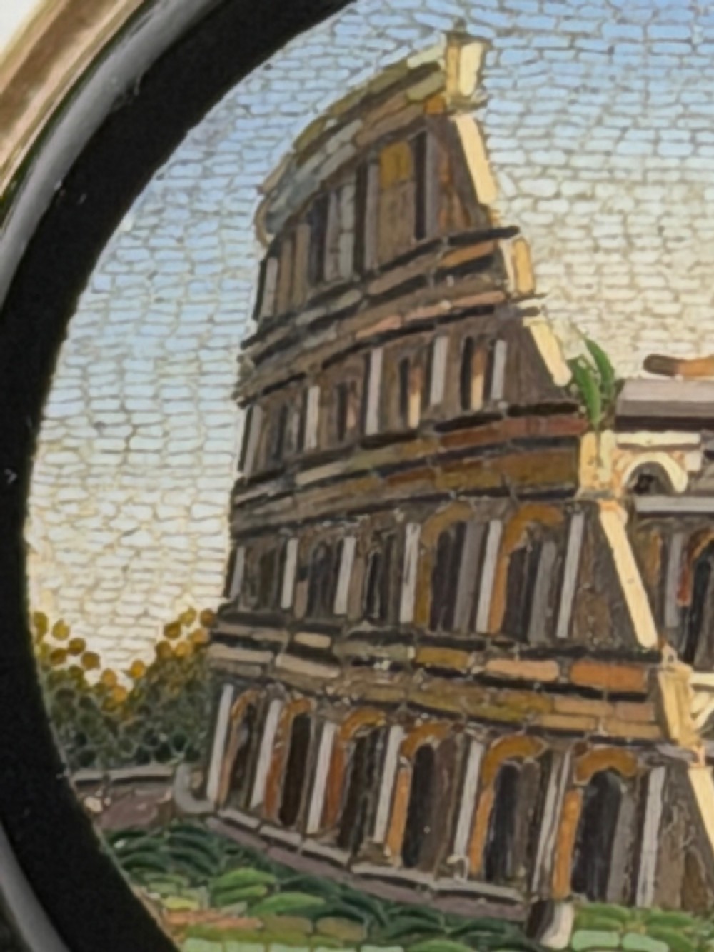 An oval nineteenth-century micromosaic brooch set in a yellow gold bezel depicting the Roman Colosseum against a light blue sky within a black surround. View IX