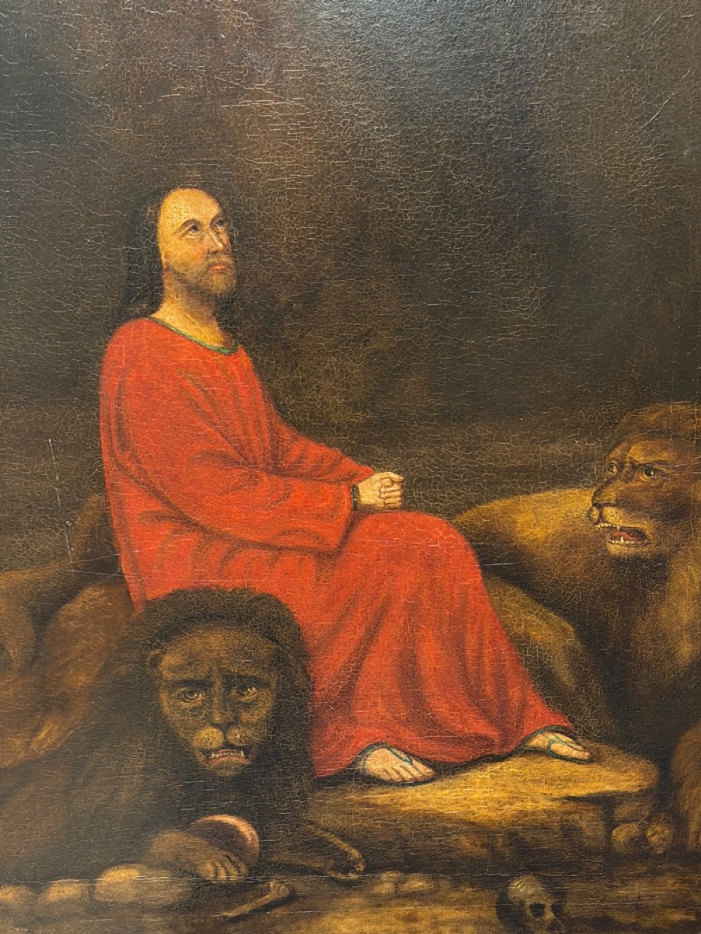 A framed Victorian oil painting depicting Daniel in a red robe seated inside a dark cavern surrounded by lions. View II