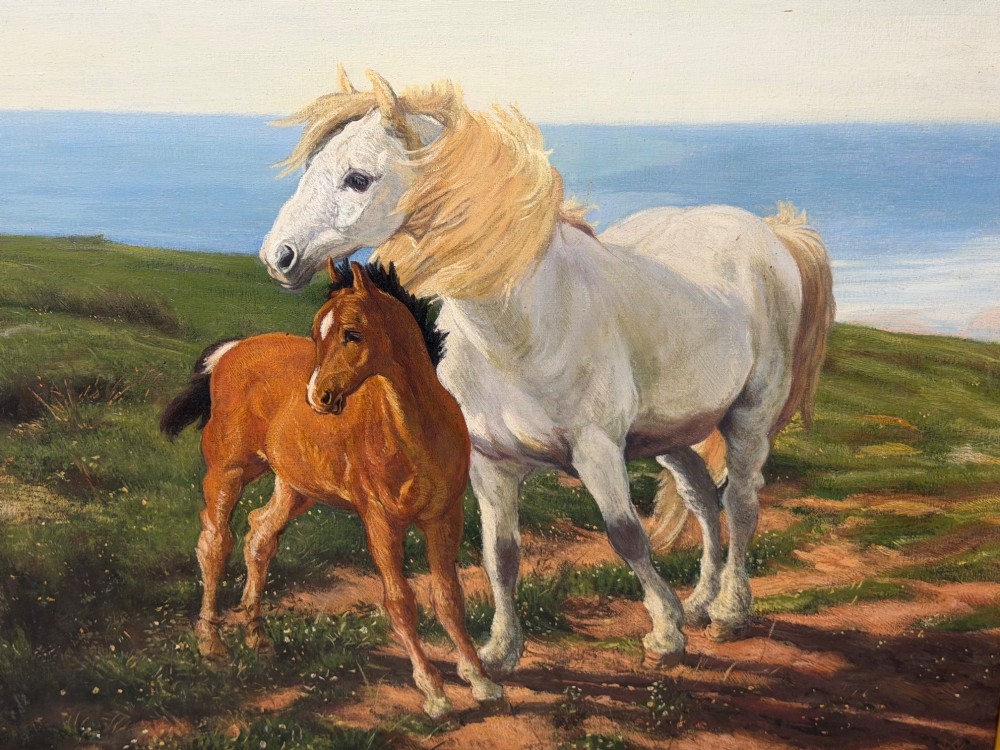 A framed oil painting featuring a grey mare standing beside a young chestnut foal on a grassy coastal headland overlooking the sea. View VI
