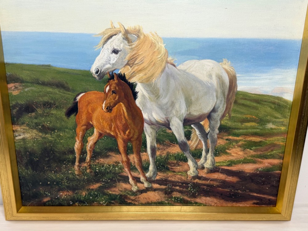 A framed oil painting featuring a grey mare standing beside a young chestnut foal on a grassy coastal headland overlooking the sea. View XIV