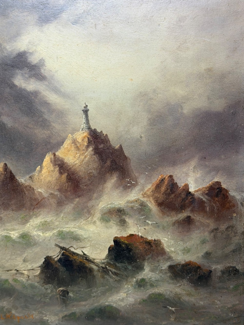 A vertical oil painting framed in carved gold leaf depicting La Corbiere lighthouse atop jagged rocks amidst a stormy grey sea with a shipwreck in the foreground. View V