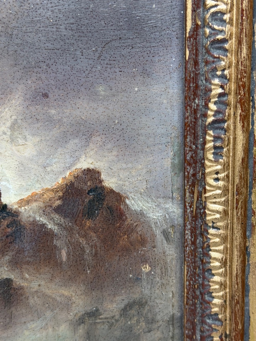 A vertical oil painting framed in carved gold leaf depicting La Corbiere lighthouse atop jagged rocks amidst a stormy grey sea with a shipwreck in the foreground. View X