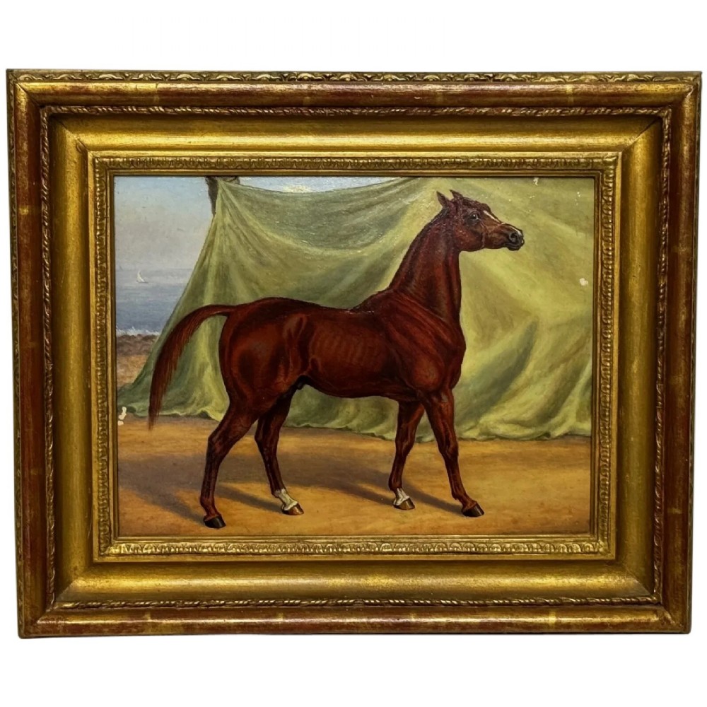 An antique oil painting depicting a chestnut Arabian horse standing in profile against a green draped backdrop within a moulded gold giltwood frame.