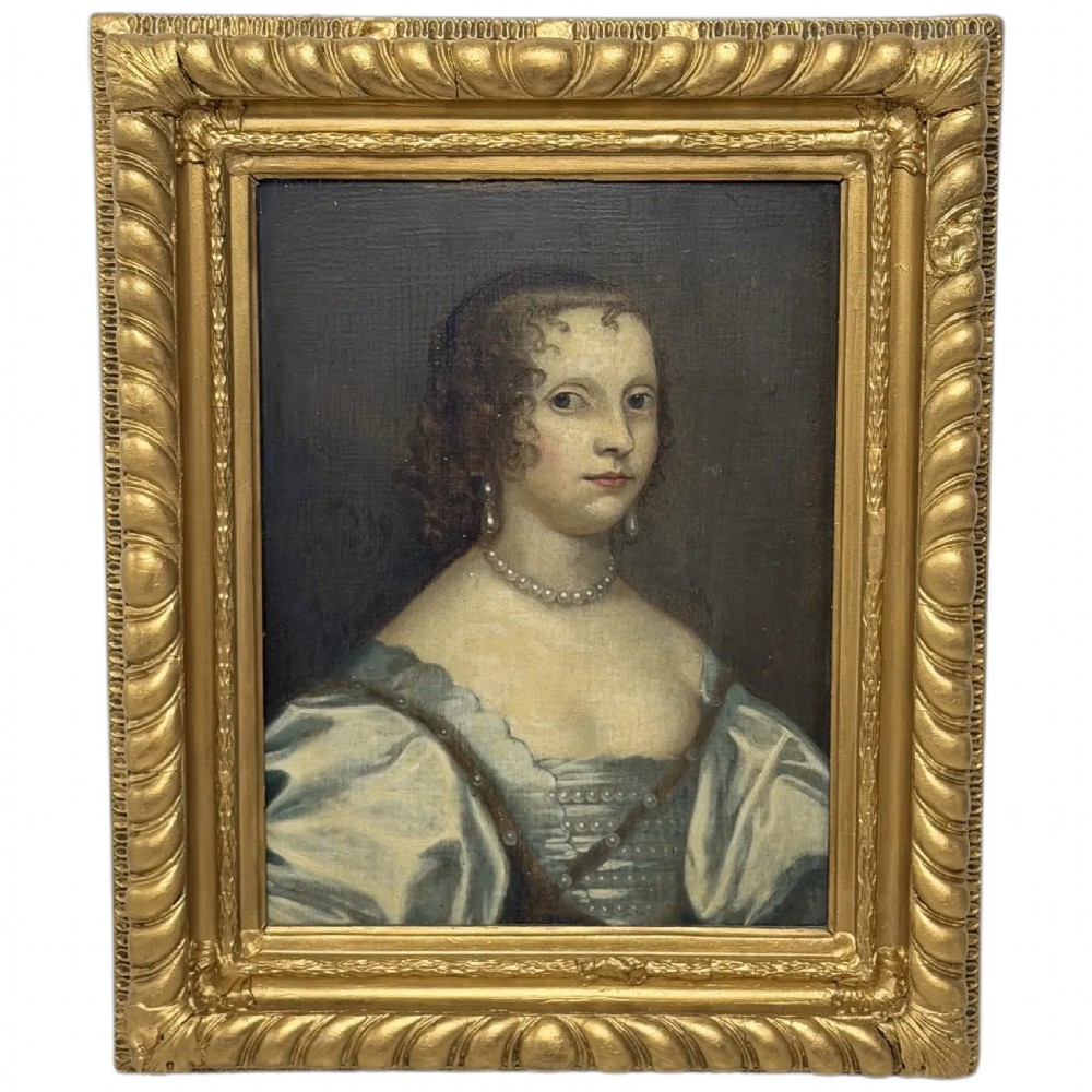 A 17th-century oil portrait painting on an oak panel depicting a woman with dark ringlets and pearl jewellery in a gadrooned gold leaf frame.