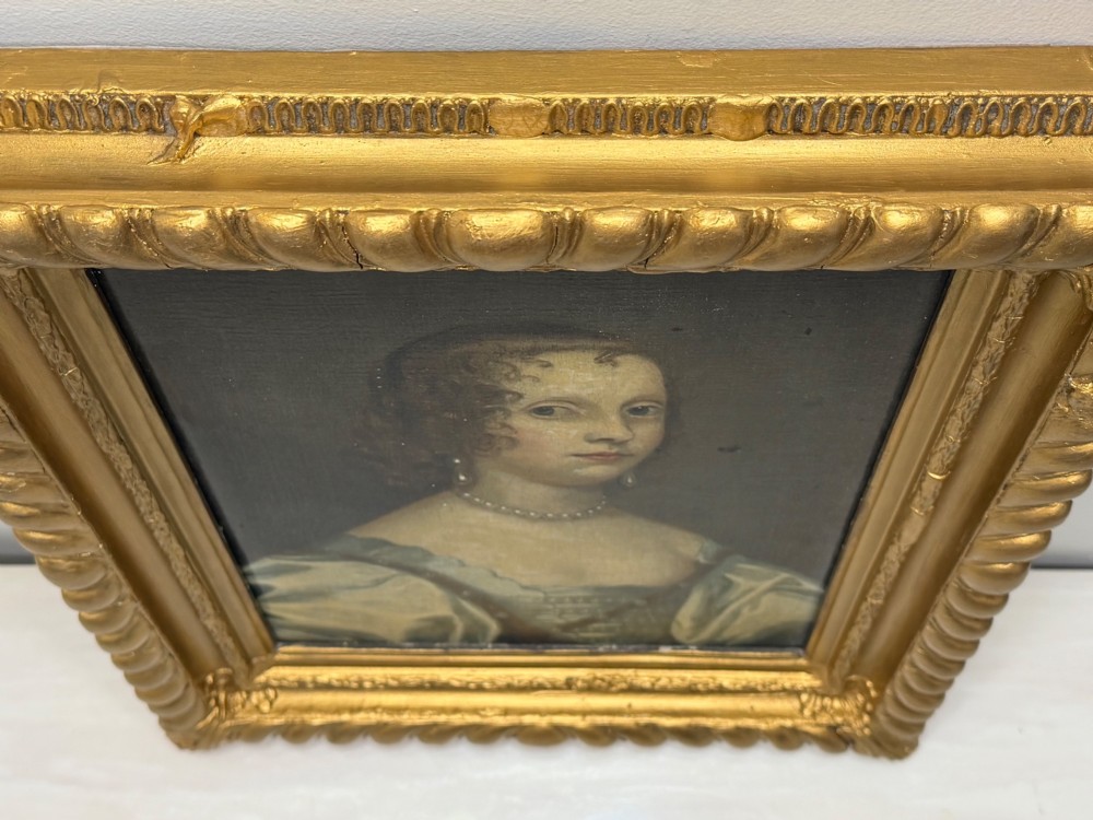 A 17th-century oil portrait painting on an oak panel depicting a woman with dark ringlets and pearl jewellery in a gadrooned gold leaf frame. View III