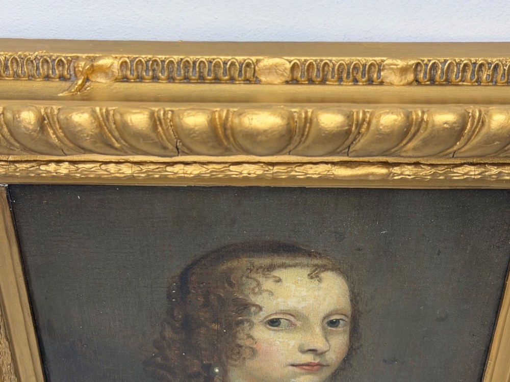 A 17th-century oil portrait painting on an oak panel depicting a woman with dark ringlets and pearl jewellery in a gadrooned gold leaf frame. View VI