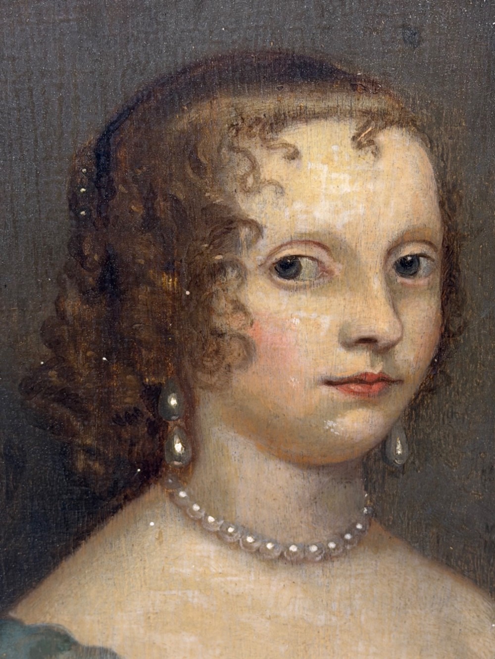 A 17th-century oil portrait painting on an oak panel depicting a woman with dark ringlets and pearl jewellery in a gadrooned gold leaf frame. View VIII