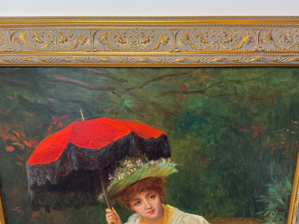 An antique oil painting depicting a seated woman in a white dress holding a red parasol, presented in an ornate carved gilded frame. View VI