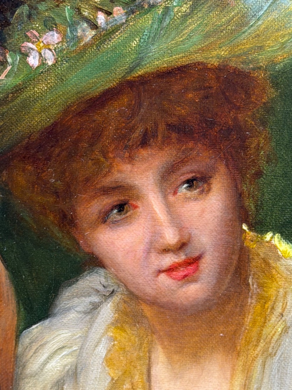 An antique oil painting depicting a seated woman in a white dress holding a red parasol, presented in an ornate carved gilded frame. View X