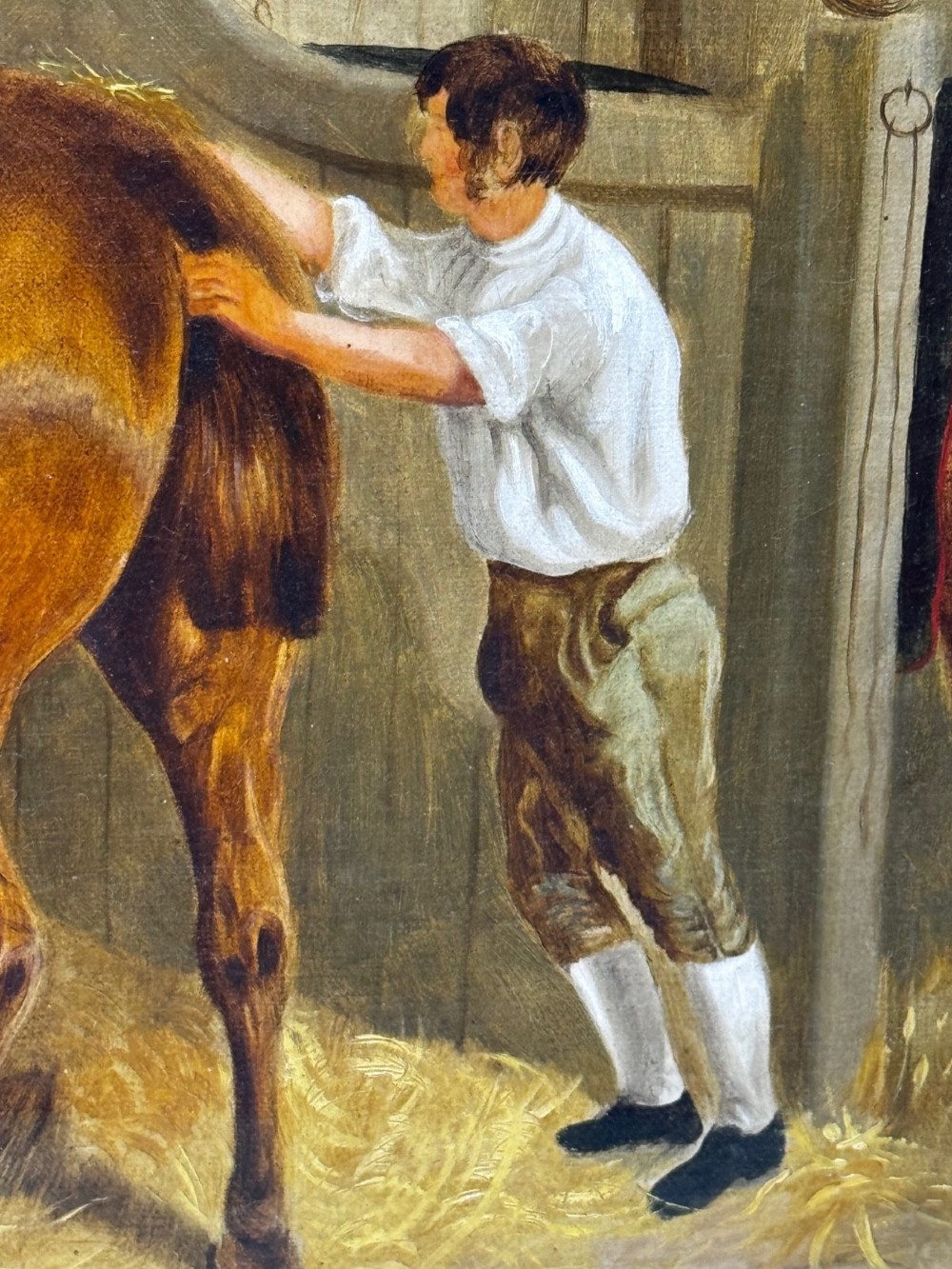 A horizontal oil painting depicting grooms tending to horses inside a stable block, housed within a fluted gilt wood frame. View XII