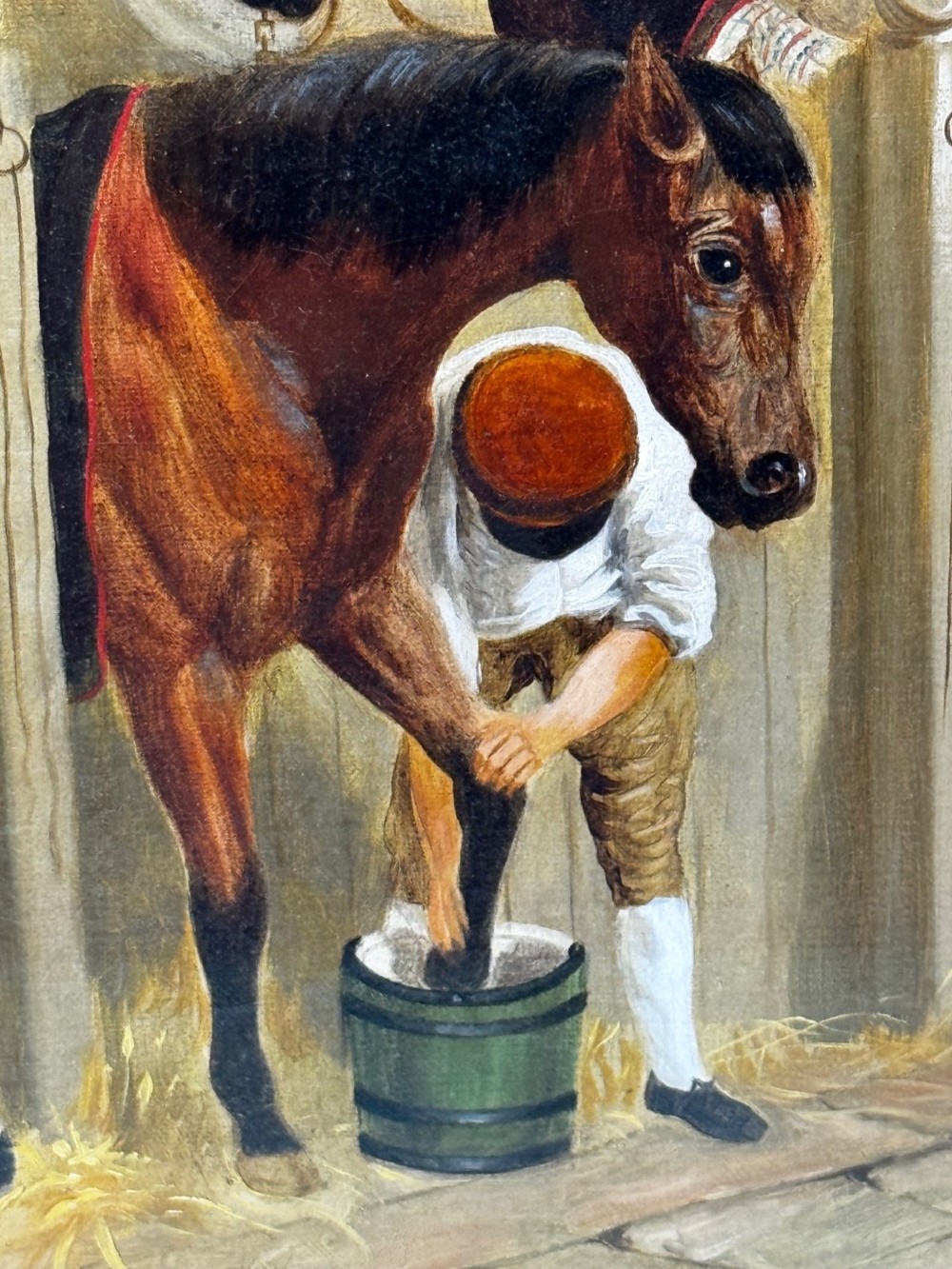 A horizontal oil painting depicting grooms tending to horses inside a stable block, housed within a fluted gilt wood frame. View XV