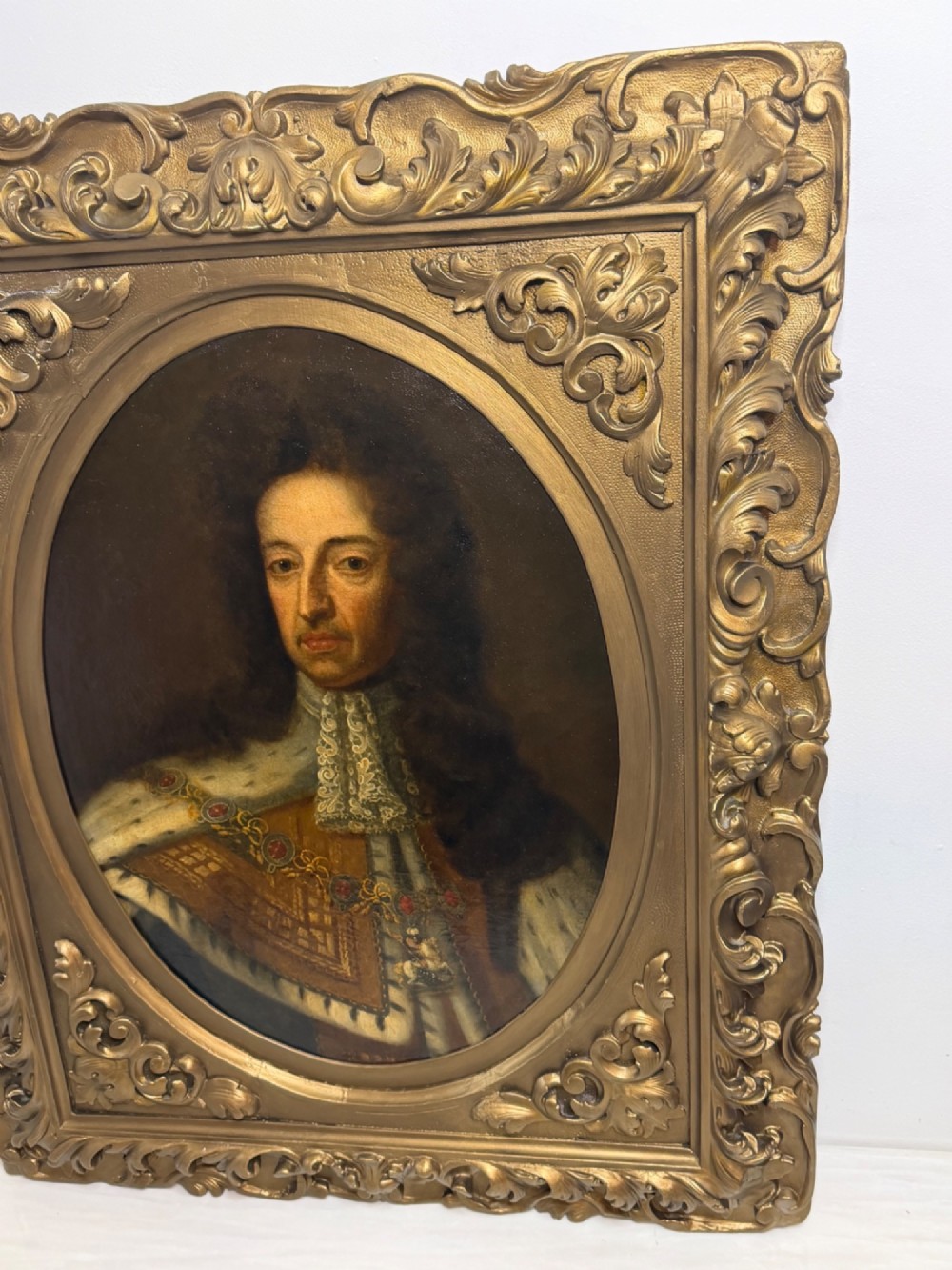 An 18th-century oil painting depicting King William III in a curled wig and ermine cloak, set within an oval aperture inside an ornate rectangular gold carved frame. View III